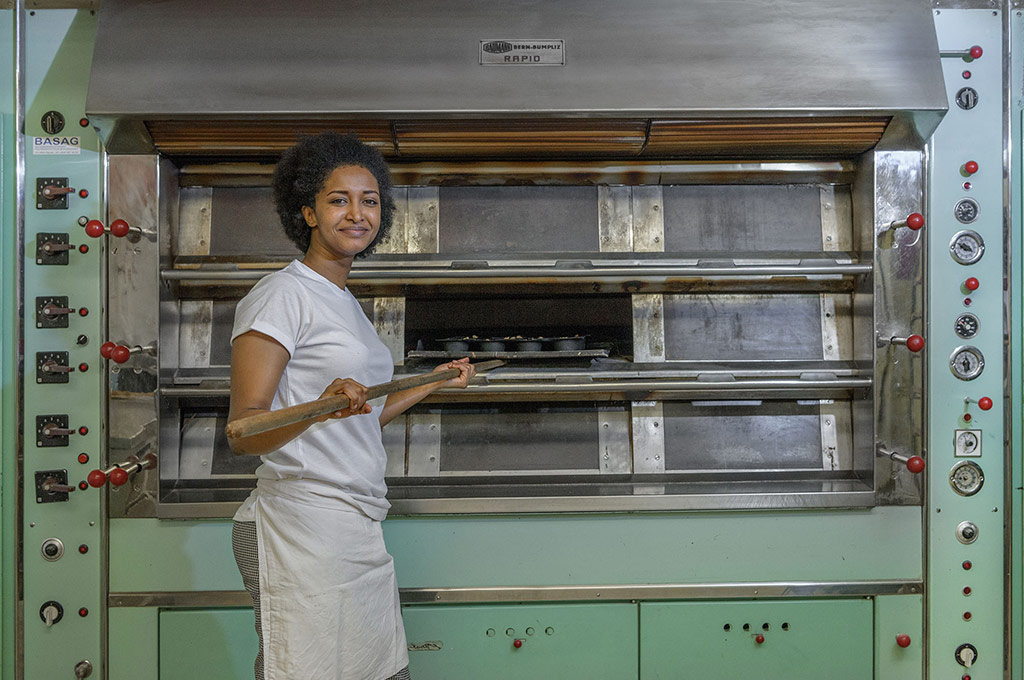 A young woman stands in front of an oven.