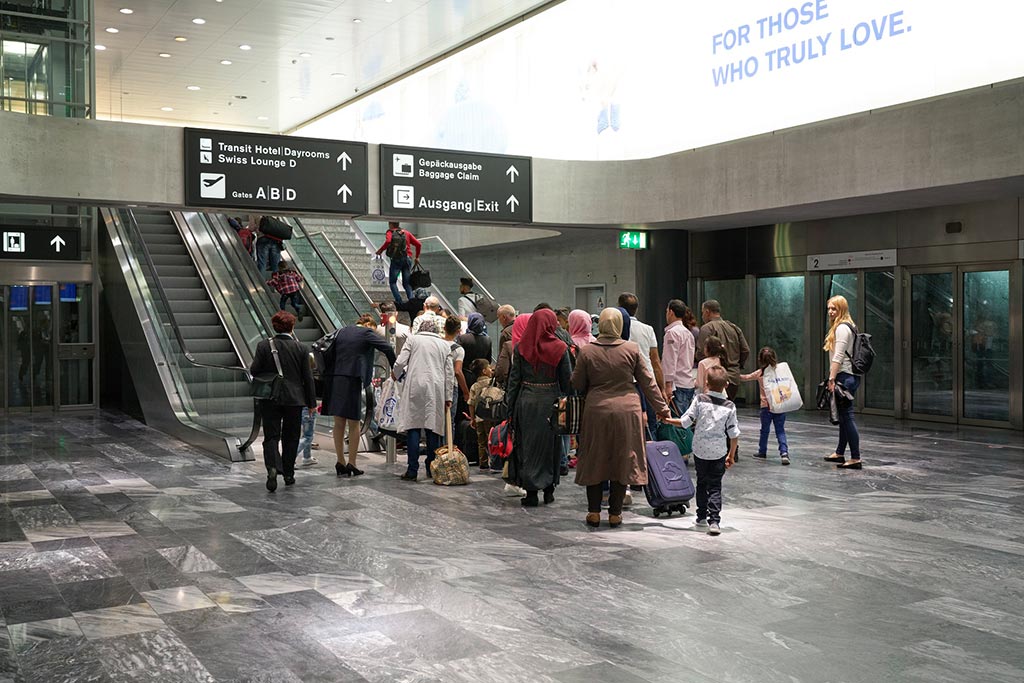 Donne velate, bambini e uomini davanti a una scala mobile all’aeroporto di Zurigo.